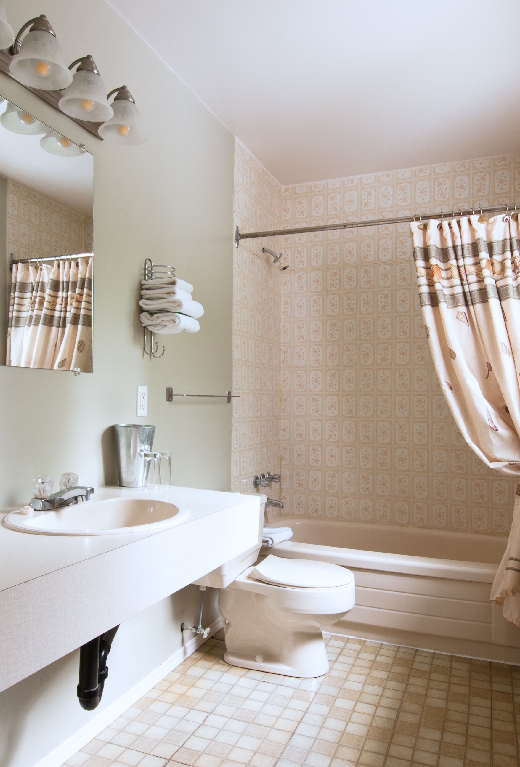 Ein Badezimmer mit Waschbecken, Spiegel, Handtuchhalter und einer Duschkabine.
