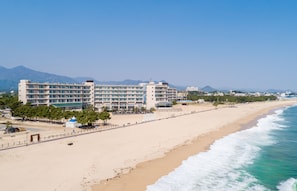 Ein Hotel direkt am Strand mit mehreren Etagen, einem Sandstrand und freiem Blick auf das Meer.