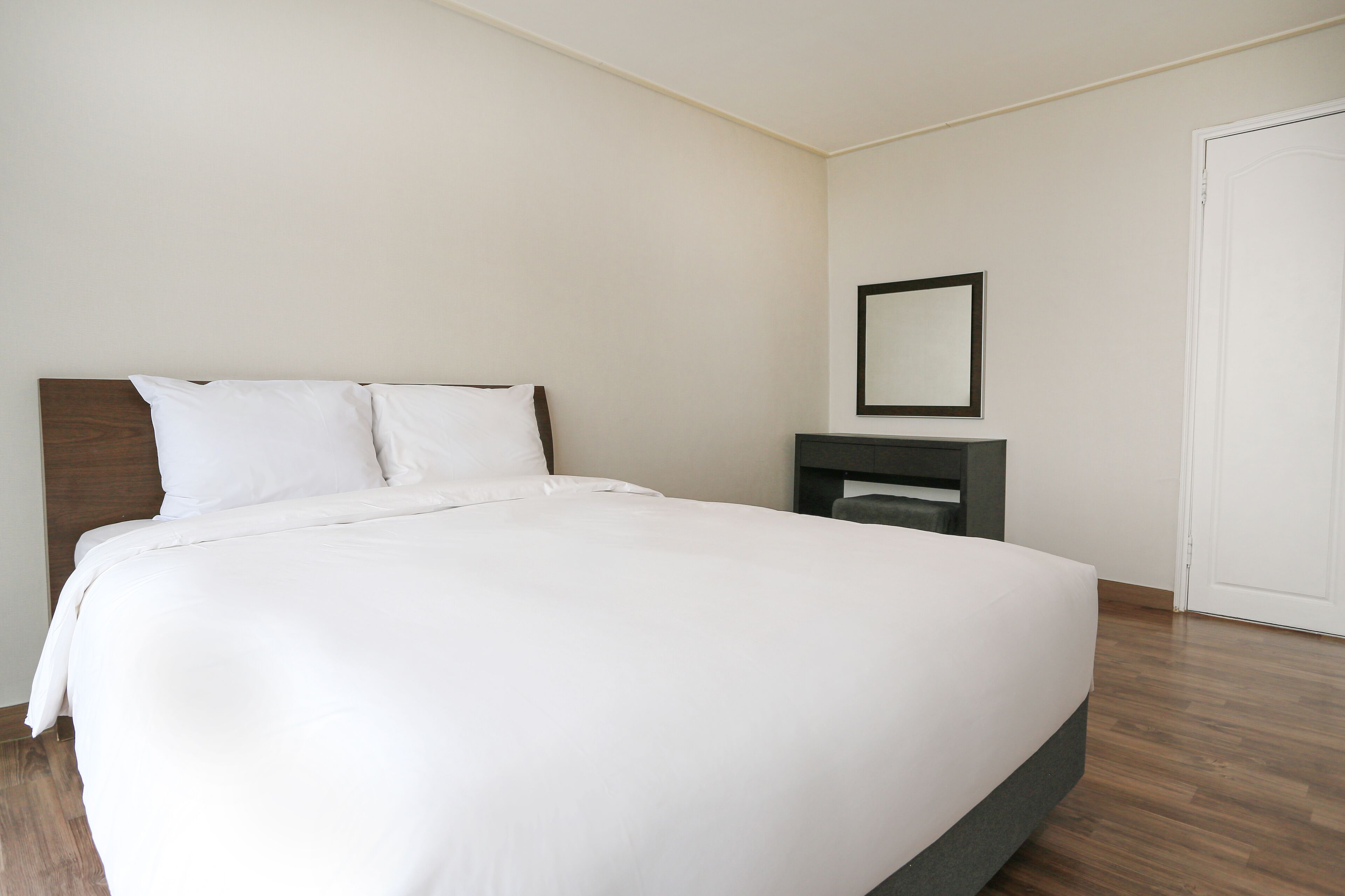 A neatly made bed with white linens in a hotel room.
