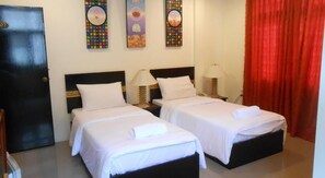 Habitación de hotel con dos camas, una puerta negra y tres obras de arte en la pared.