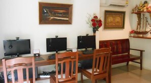 Una habitación con un escritorio de madera, tres monitores, un sofá rojo y un cuadro en la pared.