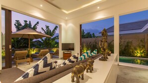 A modern living room with a sofa, cushions, a TV, and decorative items.