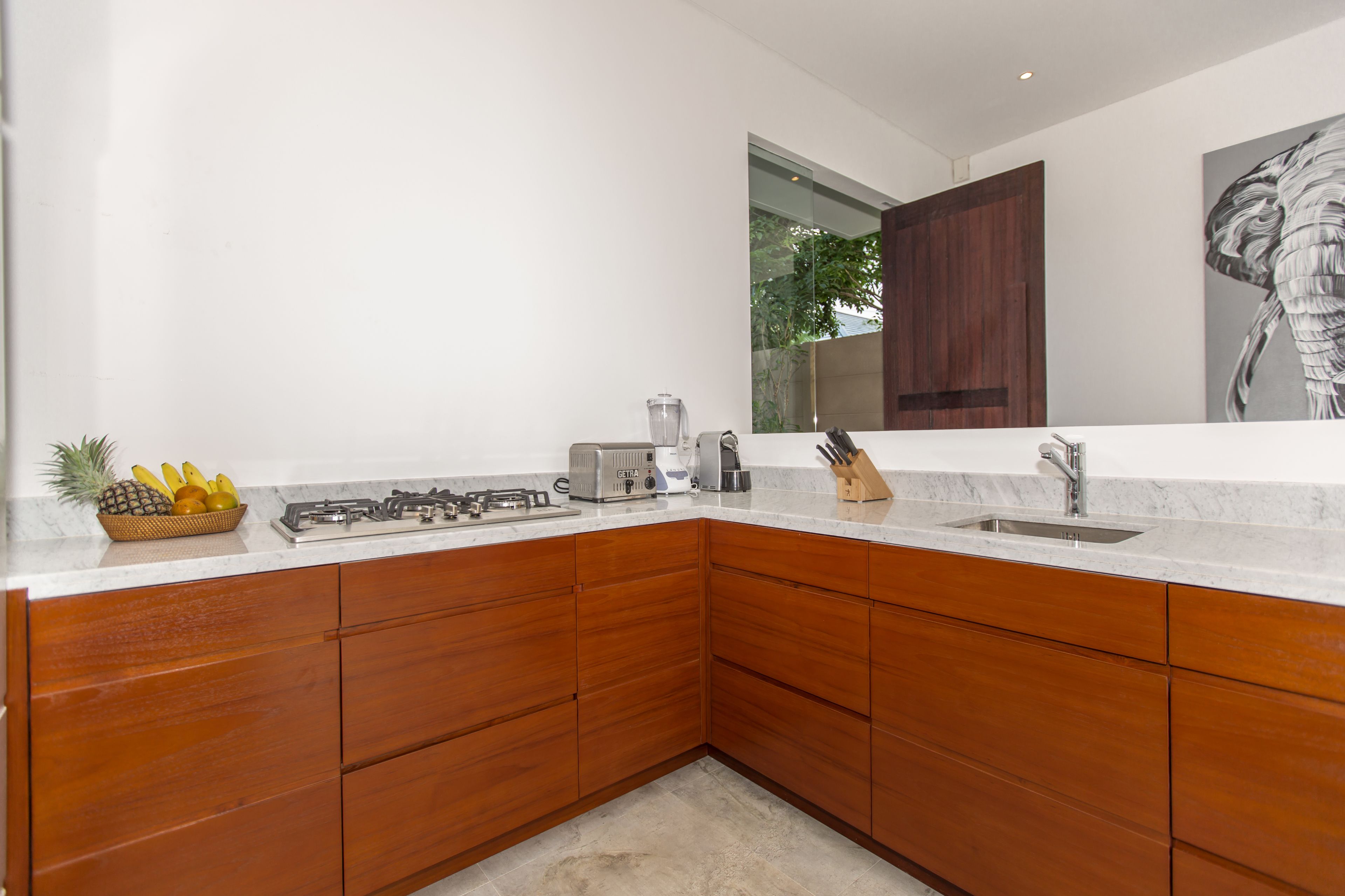 Una cocina moderna con armarios de madera, estufa a gas, un fregadero y una licuadora.