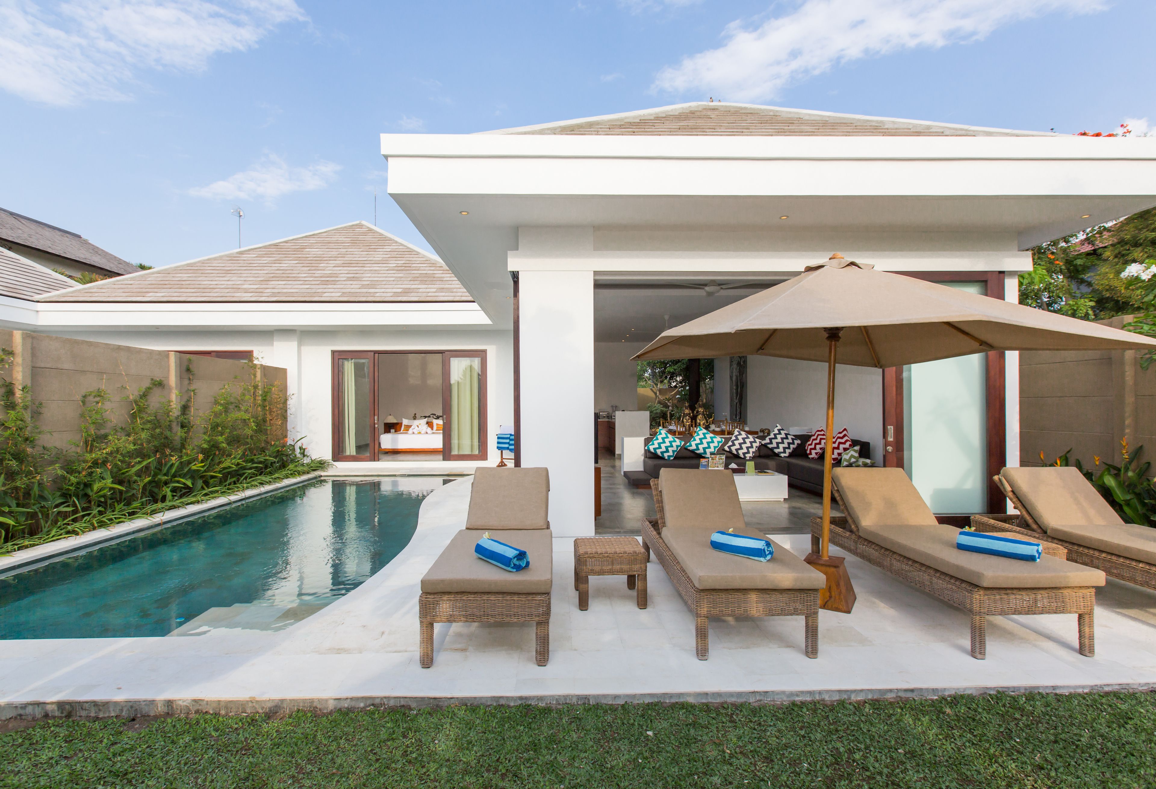 A modern outdoor pool area with lounge chairs and a covered seating area.