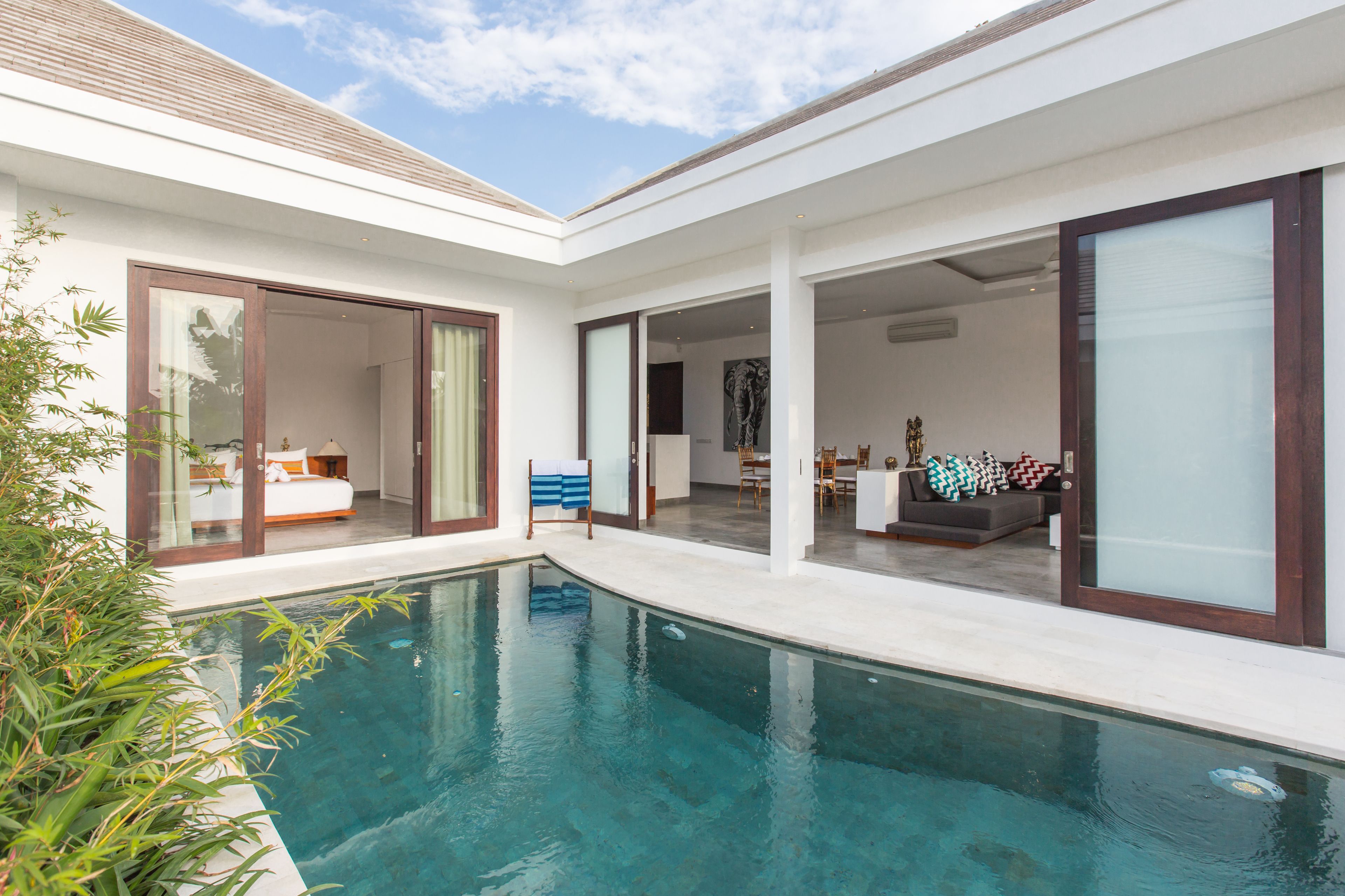 Uma casa moderna com piscina, grandes portas de vidro e um jardim bem cuidado.