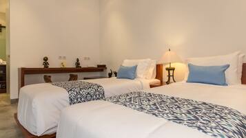 Una habitación de hotel con dos camas, una mesita de noche con lámpara y un estante pequeño con adornos.
