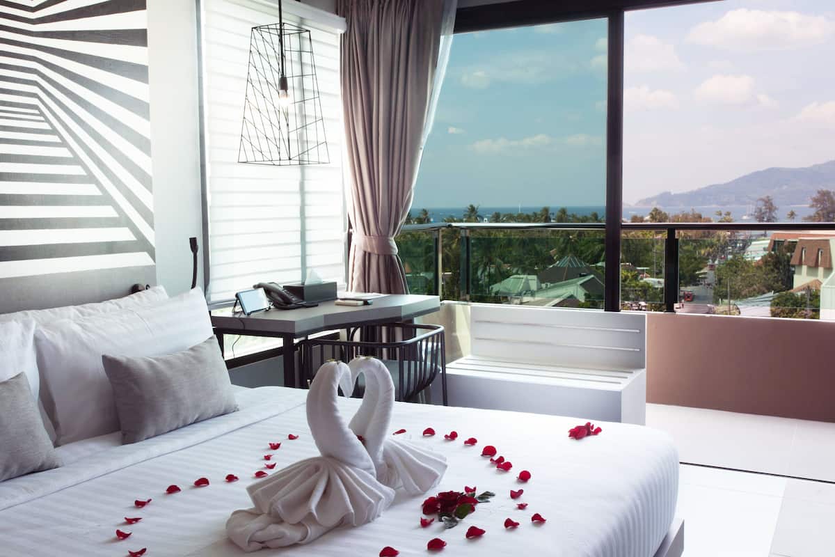 A hotel room with a bed, a desk, and a view of the ocean.