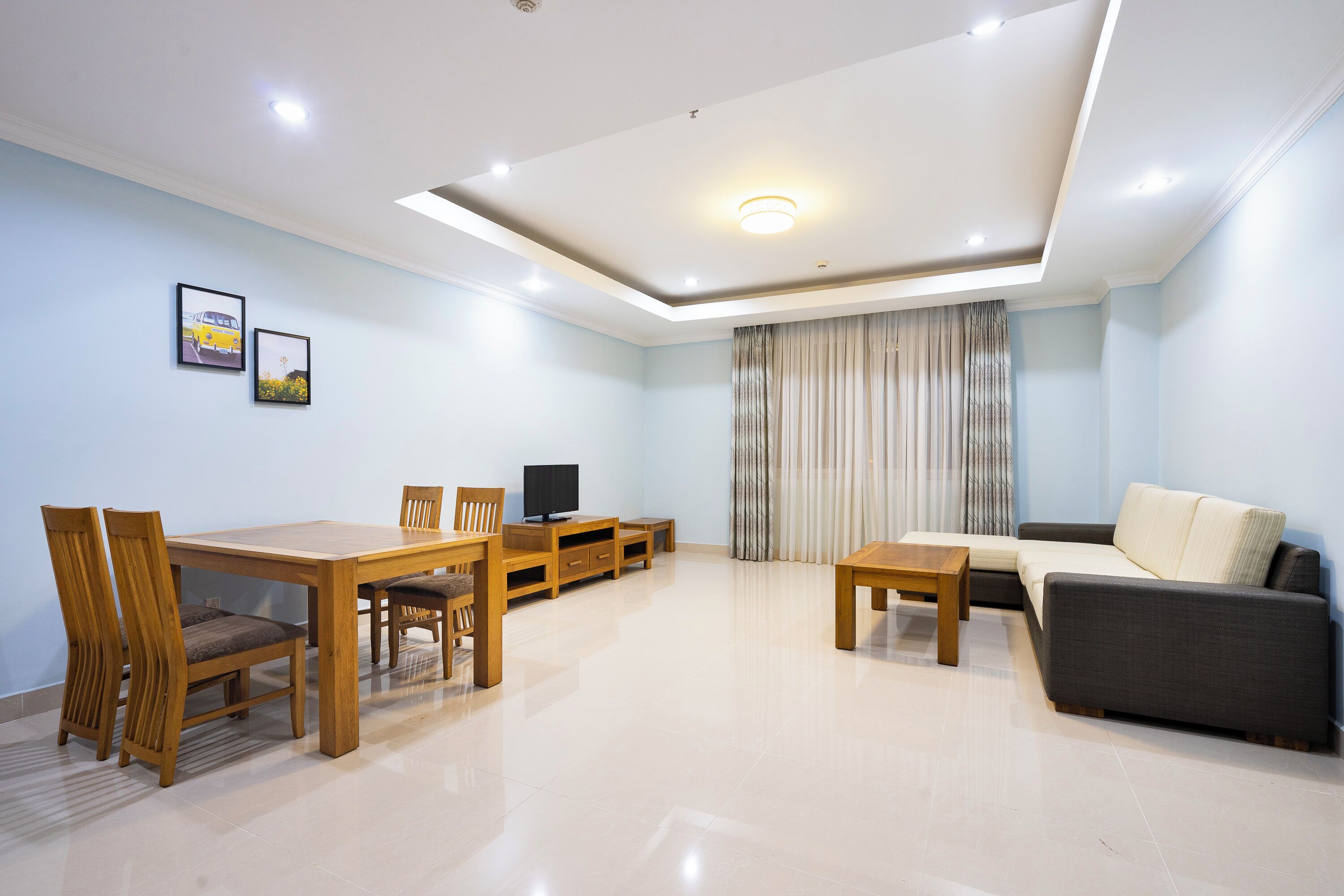 A modern living room with a dining area, a sofa, a TV, and a ceiling light.