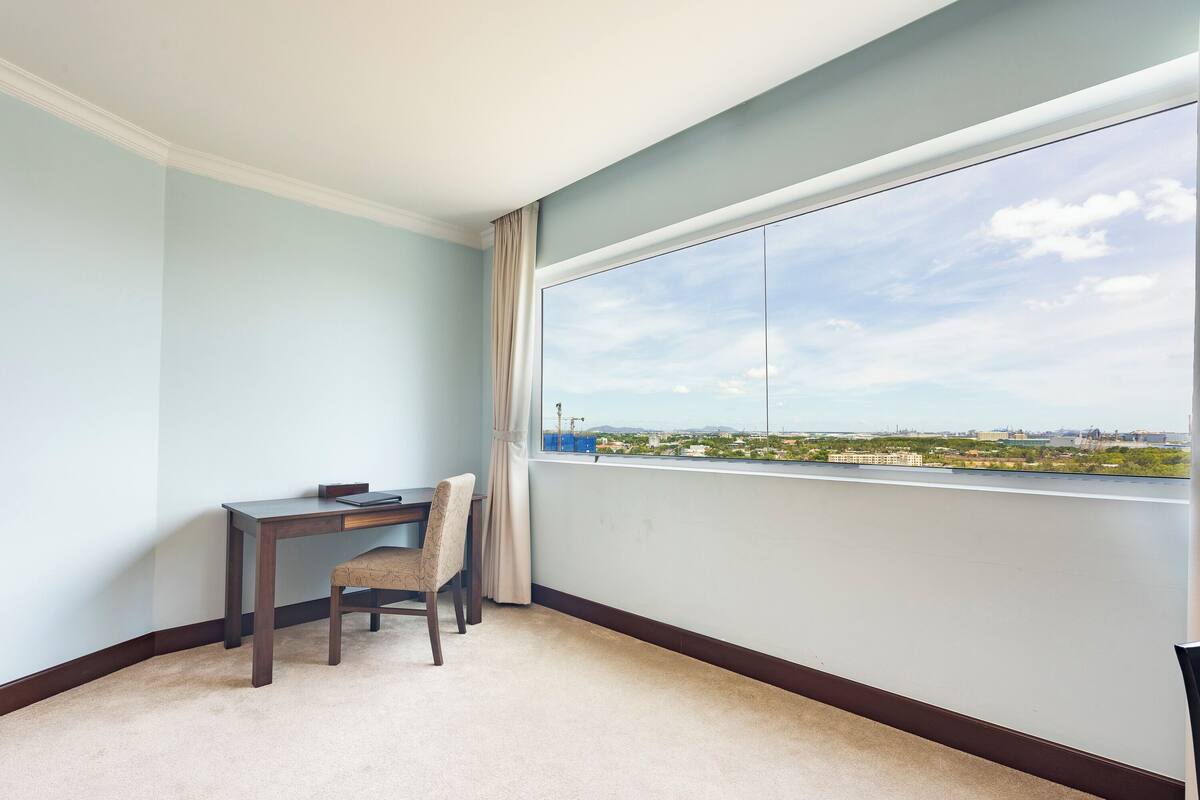 A room with a large window, a desk, and a chair.