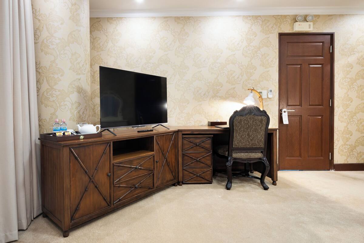 A room with a wooden desk, a television, and a chair.