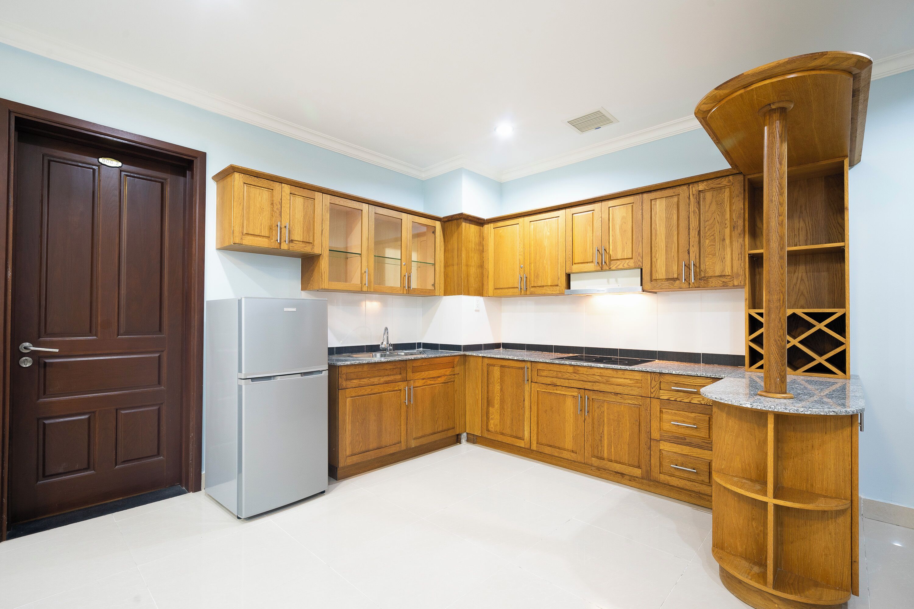 Eine Küche mit Holzausstattung, einem Kühlschrank und einer eingebauten Holzsäule.