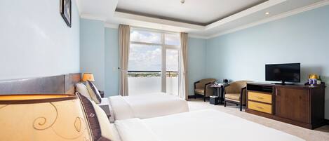 Habitación de hotel con dos camas, televisión, escritorio y vistas al exterior.