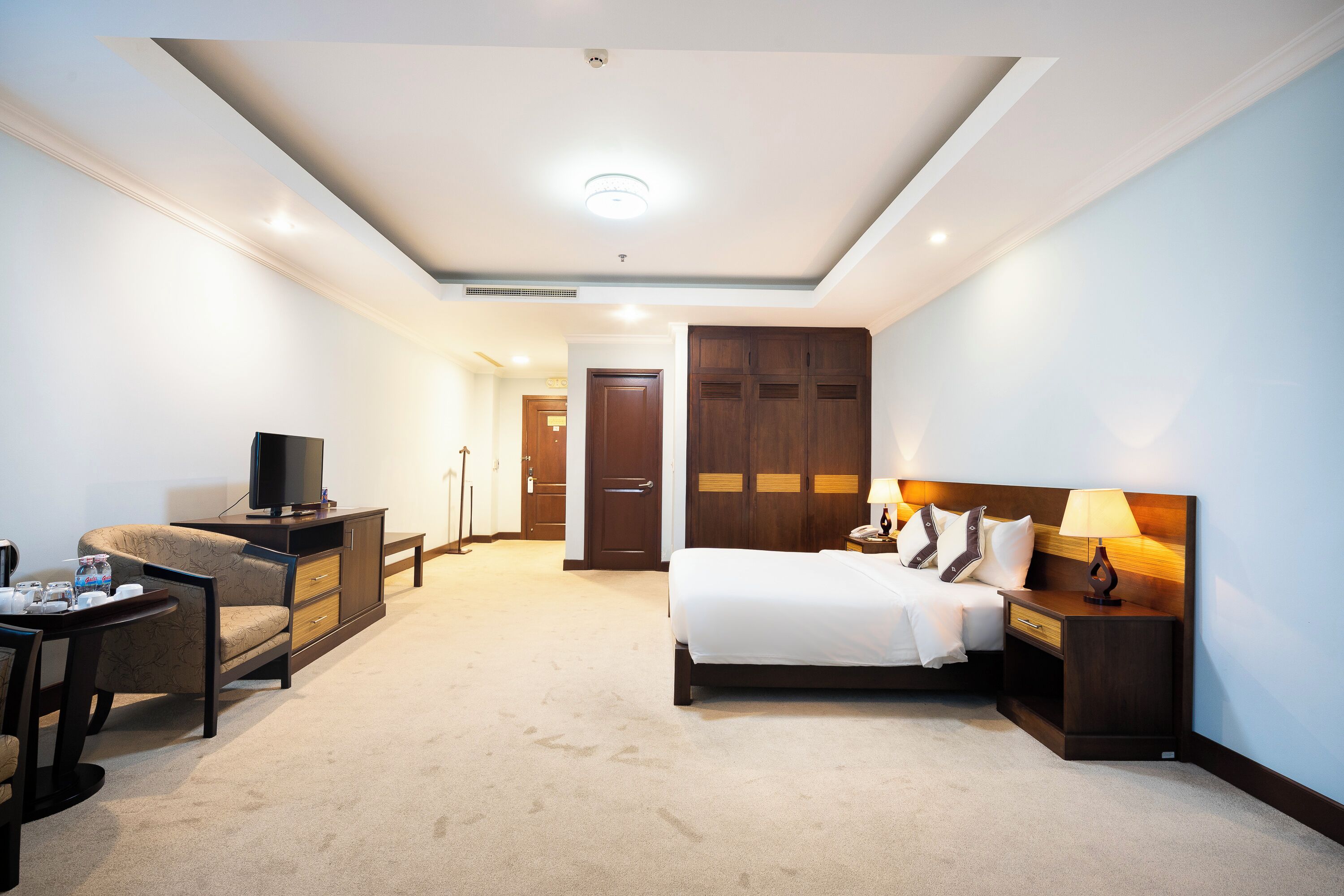 A hotel room with a bed, a TV, a desk, and a wardrobe.