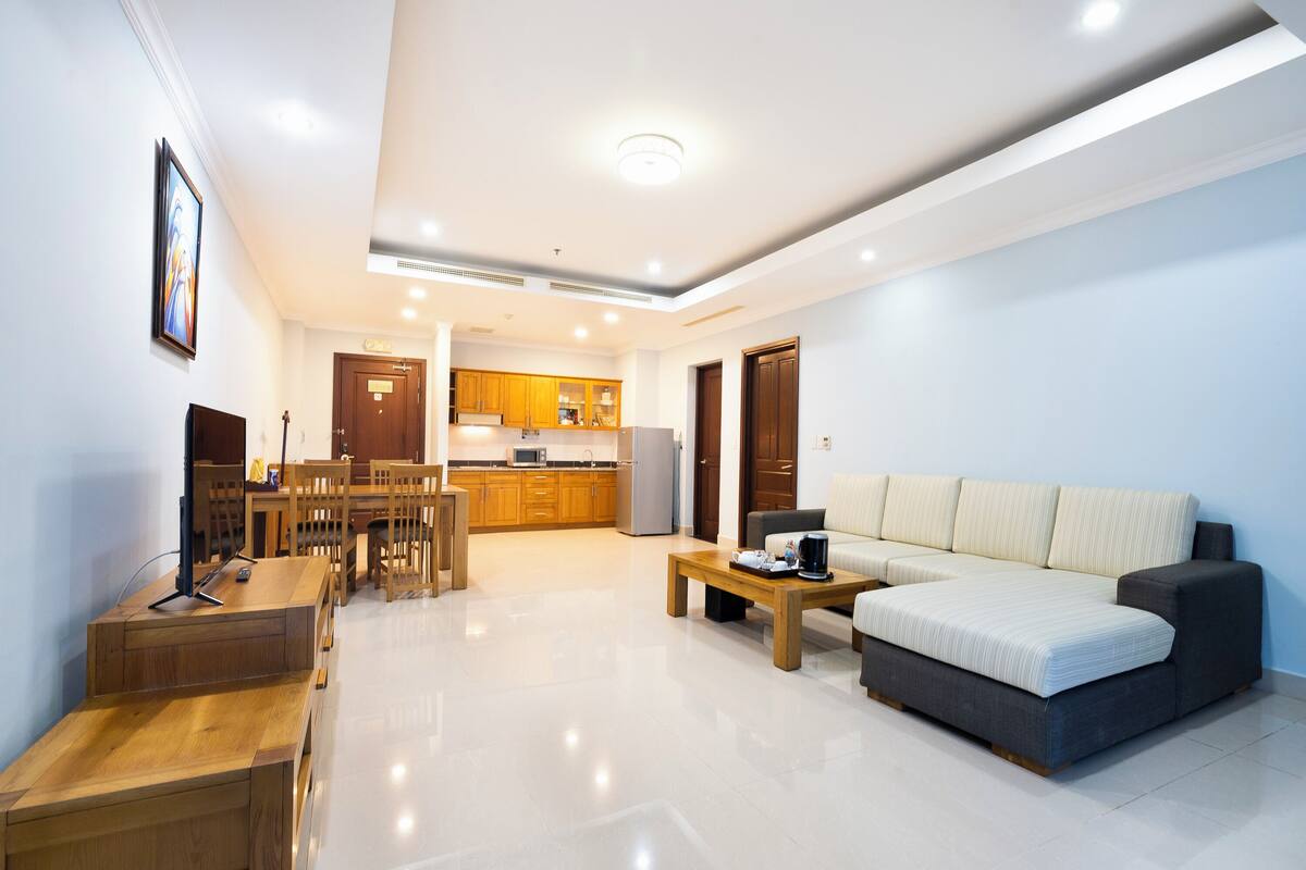 A modern living room with a sofa, coffee table, and wooden dining table.