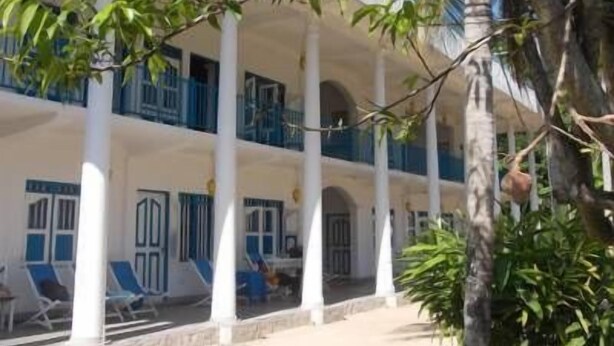 A building with white columns and blue accents, featuring multiple balconies and outdoor seating areas. - Zimmer Rest (Unawatuna)