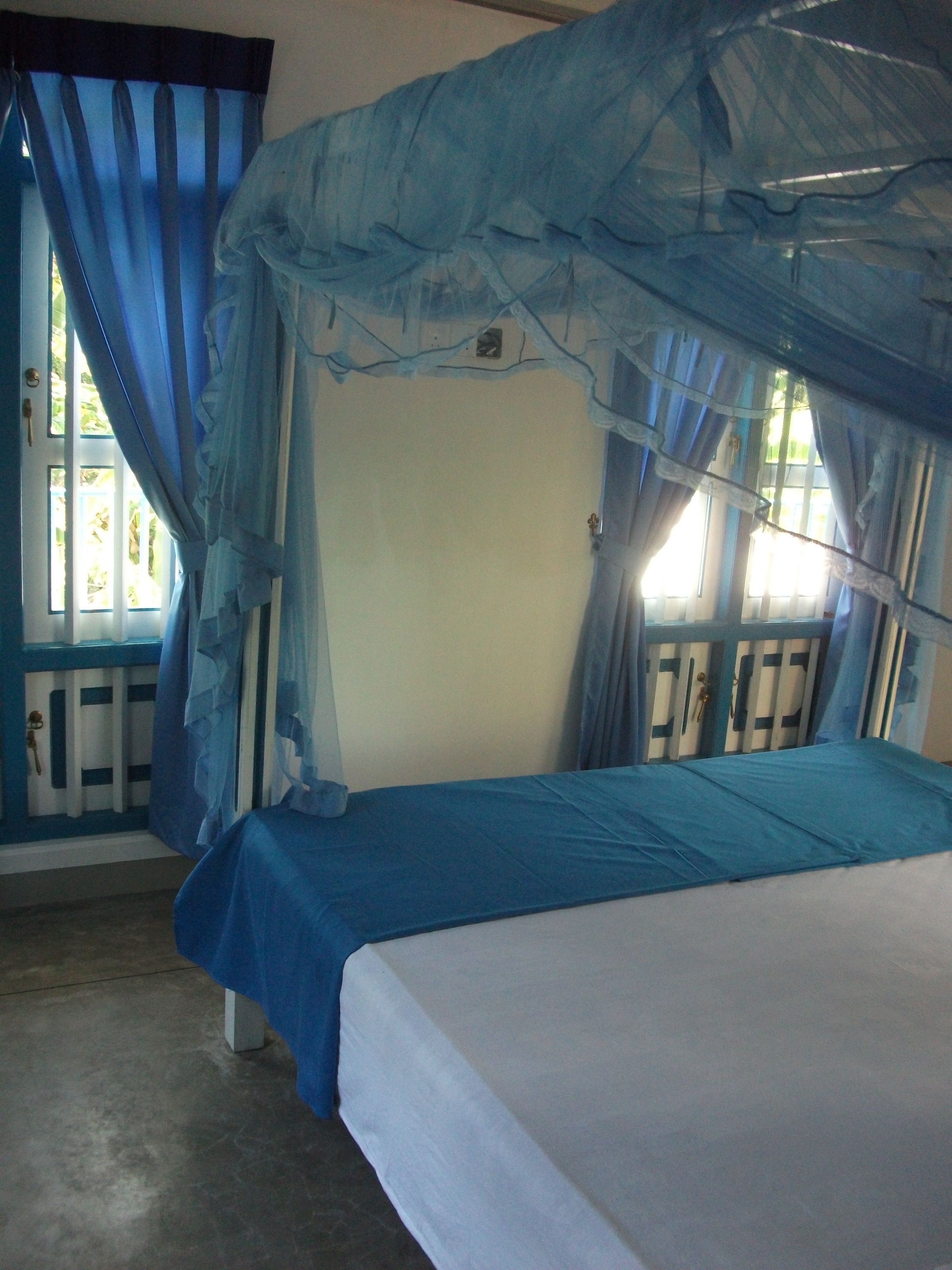 A room with a bed, a window with curtains, and a radiator.