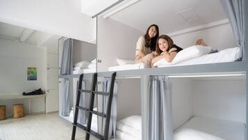 A bunk bed room with a ladder, a desk, and a bench.