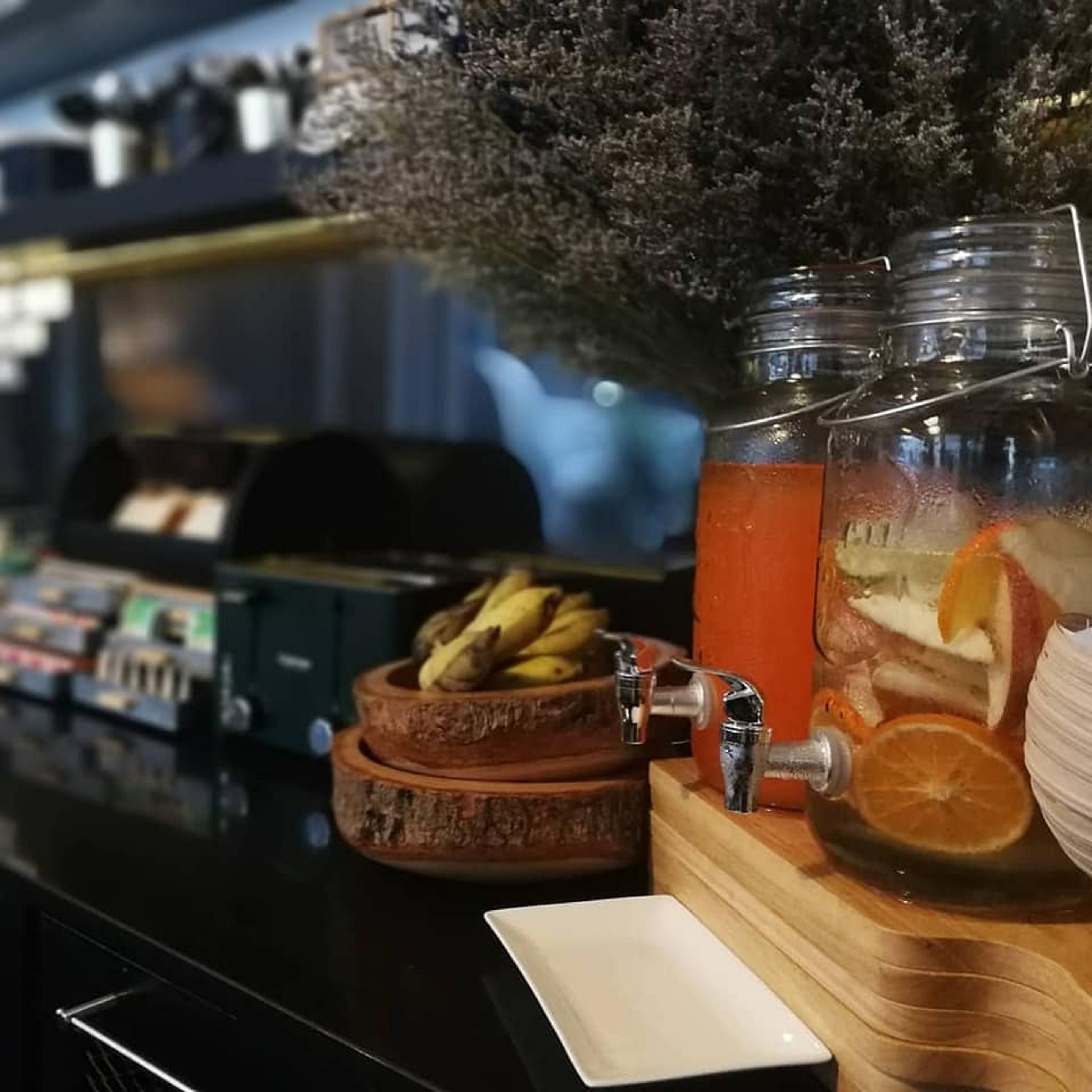 A bar area with a counter, a fruit bowl, and two large jars with a drink.