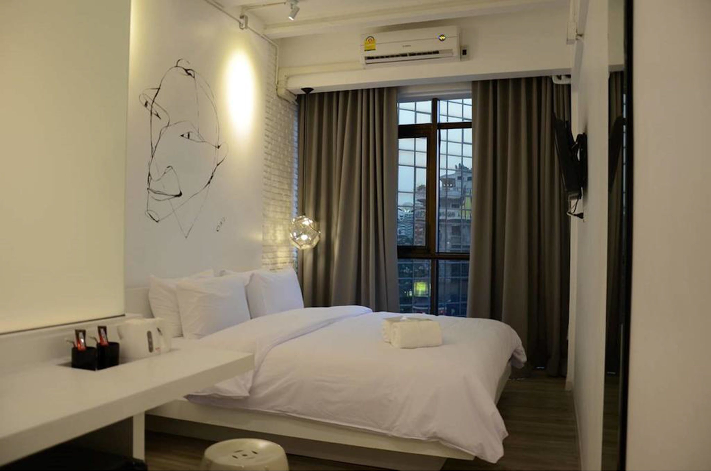 Een moderne hotelkamer met een groot bed, een witte nachtkastje, een wanddecoratie en uitzicht op de stad.