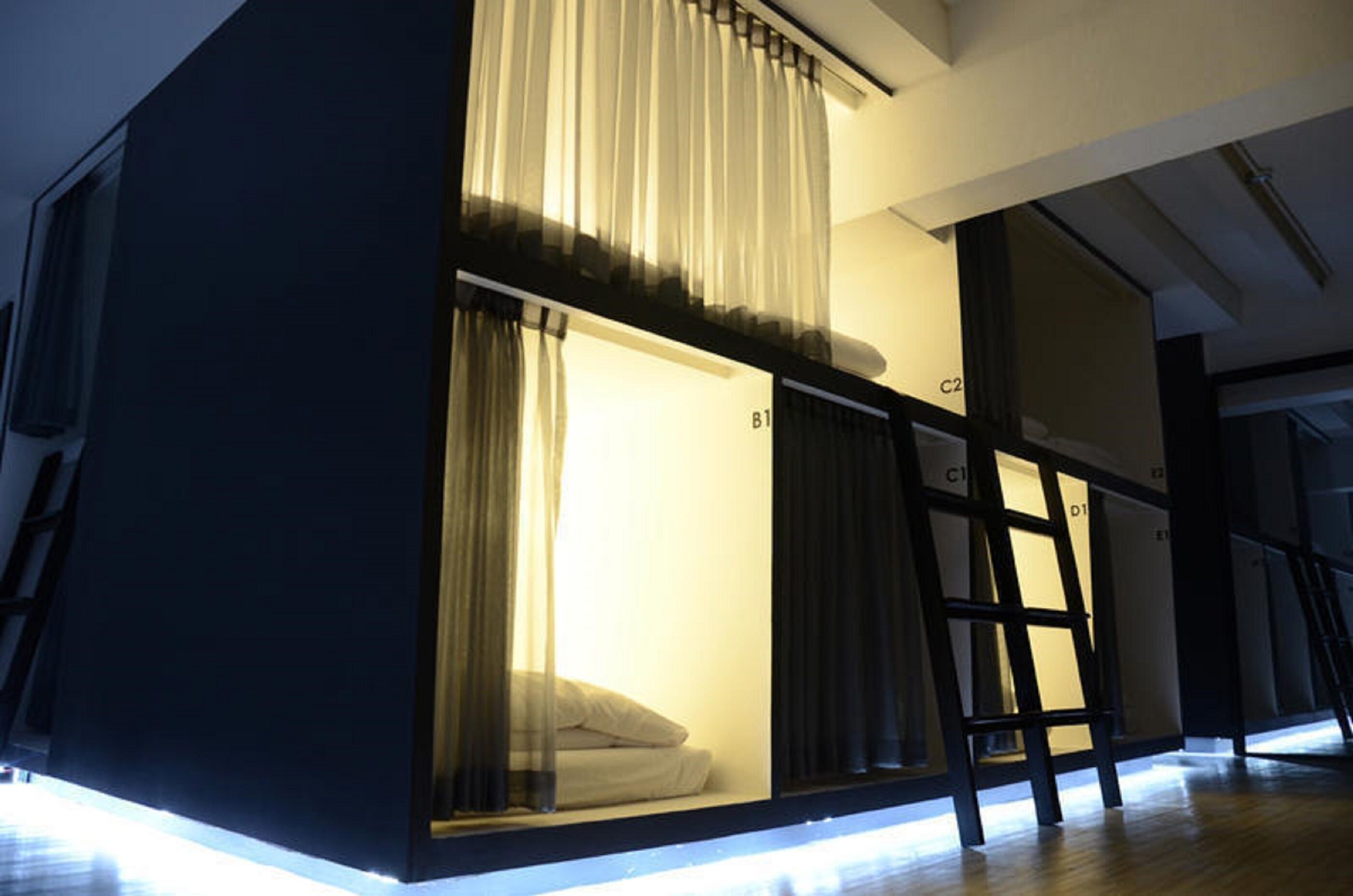A room with a bunk bed, a ladder, and a window with curtains.