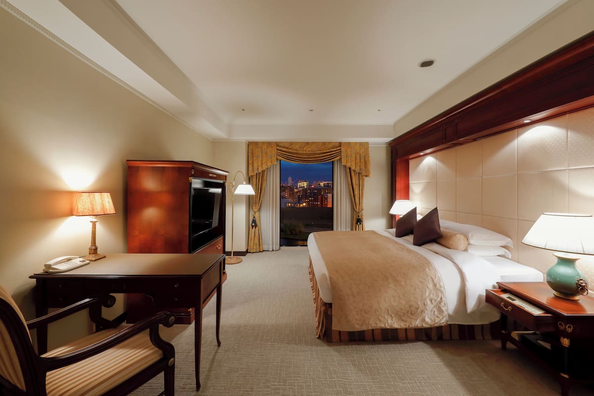 Una habitación de hotel con cama, escritorio, silla y televisor.