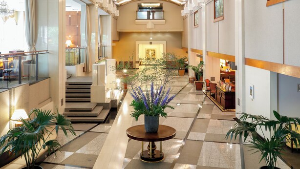 A spacious lobby with a checkered floor, a central round table with a potted plant, and a staircase leading to an upper level. - Premier Hotel Tsubaki Sapporo (Sapporo)