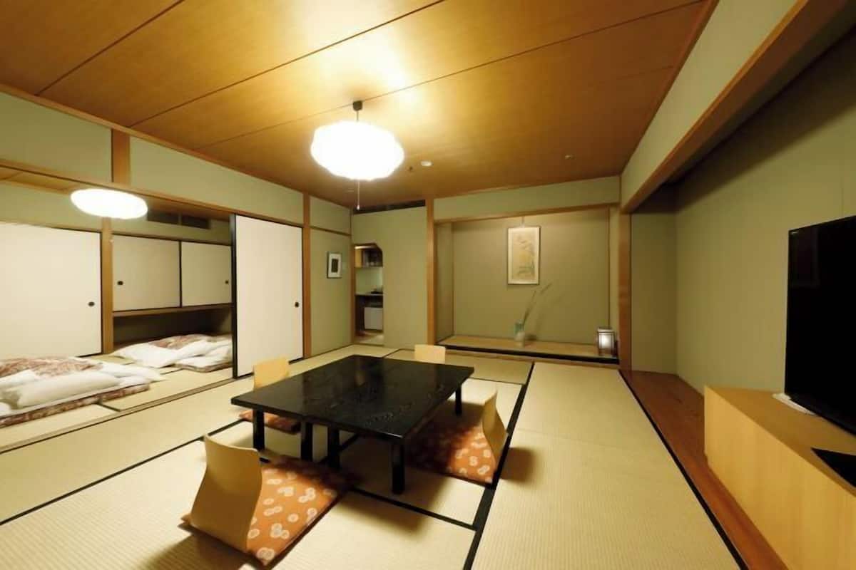 Una habitación japonesa tradicional con suelo de tatami, una mesa baja y un televisor.