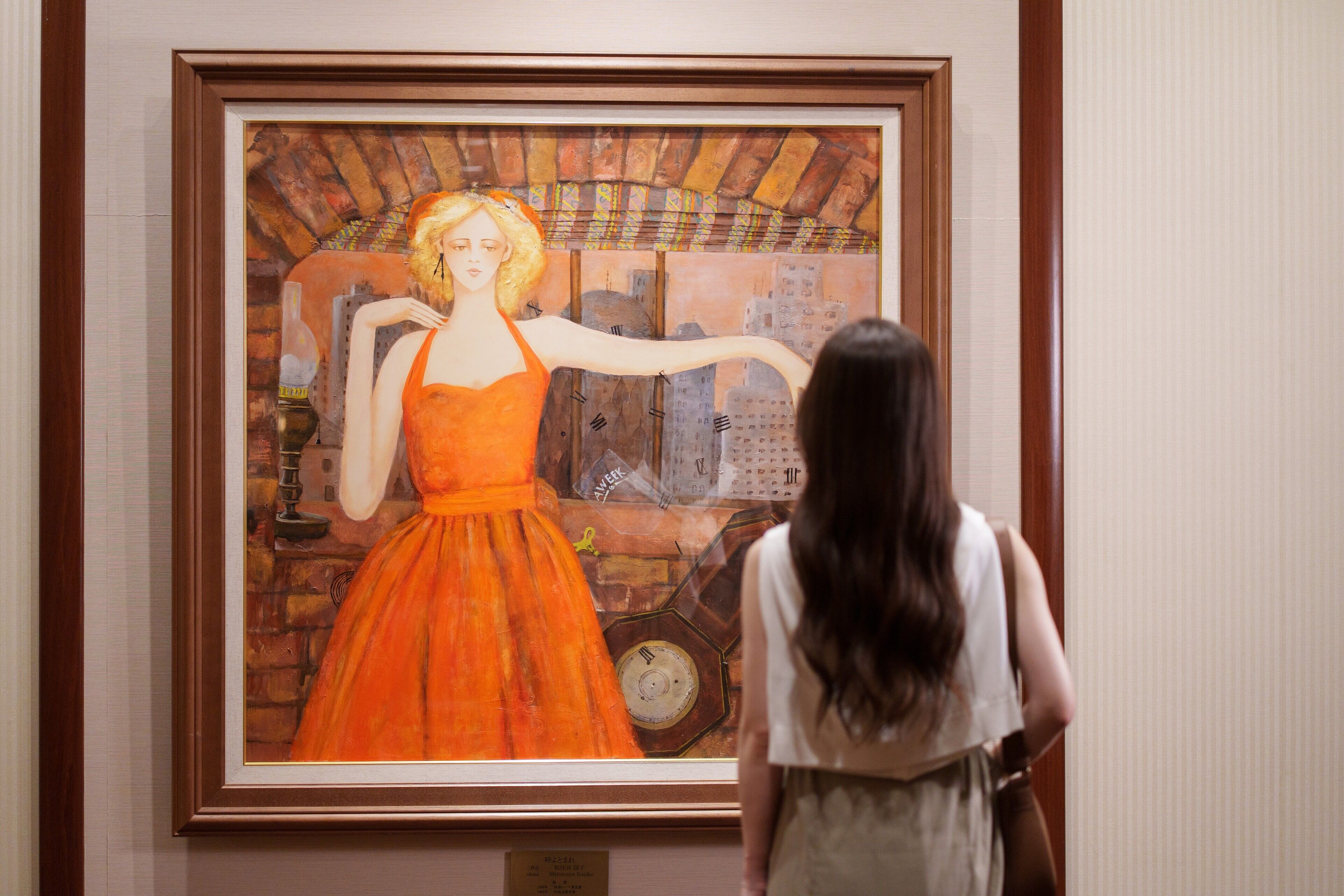 A framed painting of a woman in an orange dress.