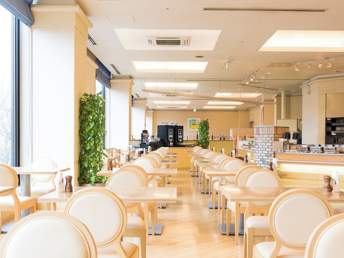 A spacious dining area with multiple tables and chairs, a coffee machine, and a counter with various items.