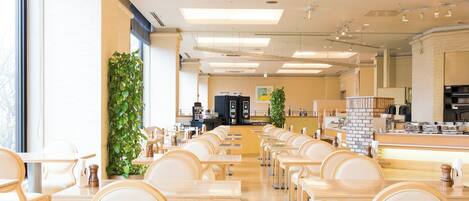 Un comedor amplio con varias mesas y sillas, una máquina de café y una encimera con distintos artículos.