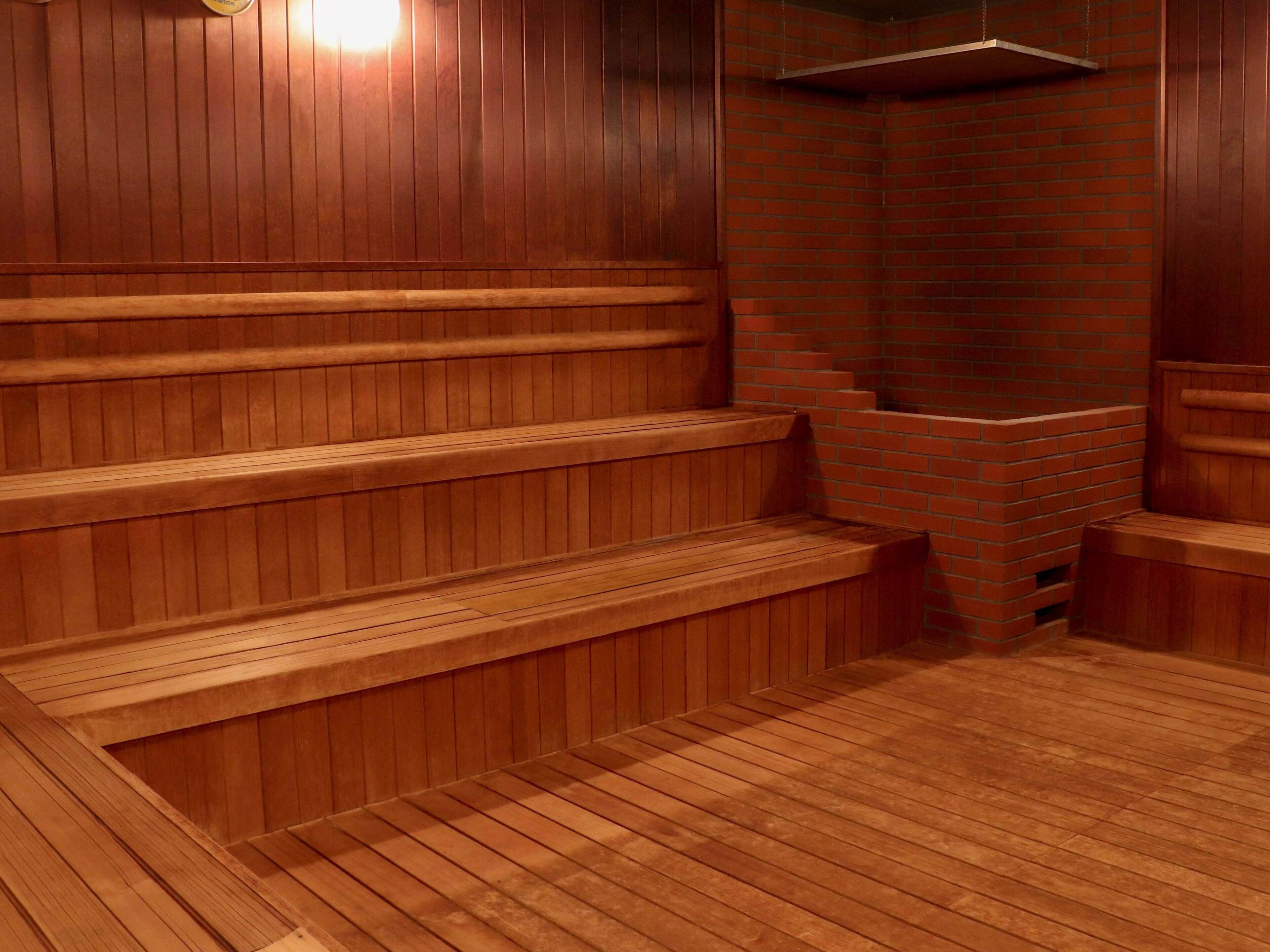 A sauna with wooden benches and a brick wall.