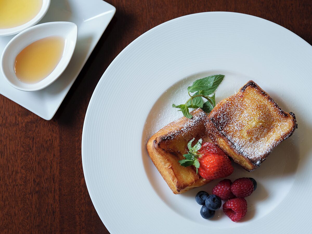 Ein Teller mit French Toast, Erdbeeren und Blaubeeren.