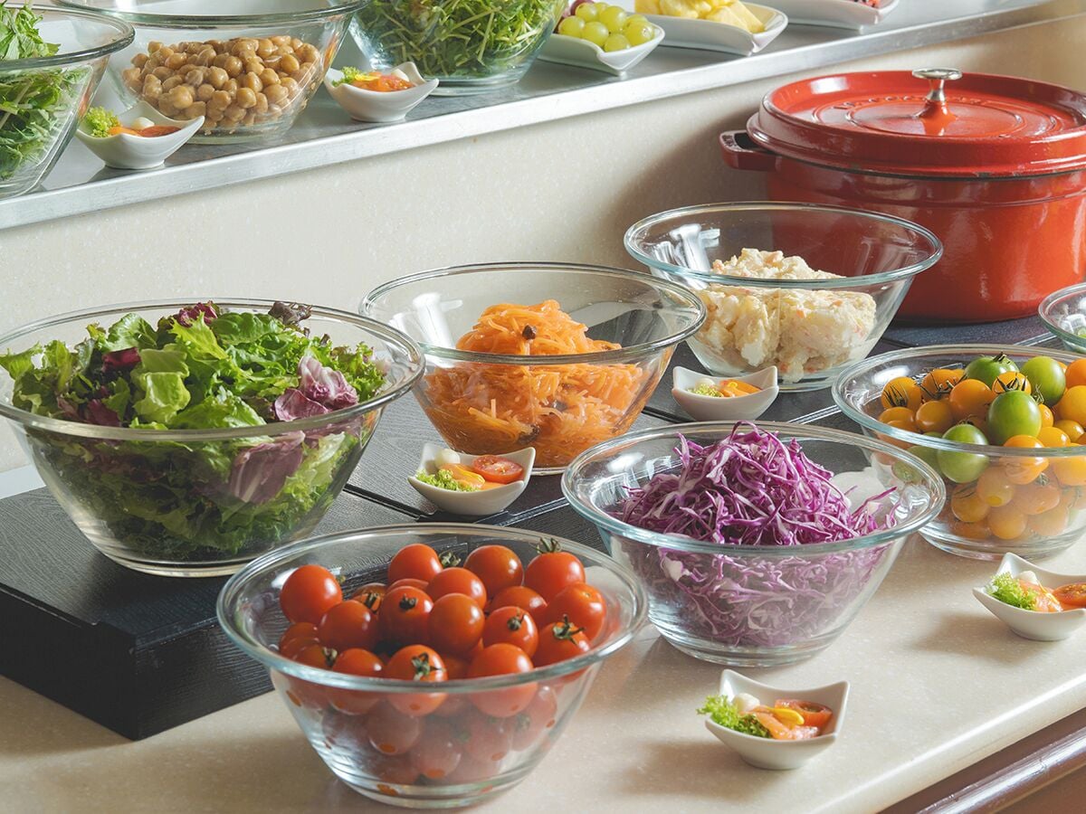 A buffet table with various food items including salads, vegetables, and fruits.