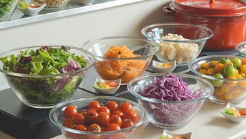 A buffet table with various food items including salads, vegetables, and fruits.
