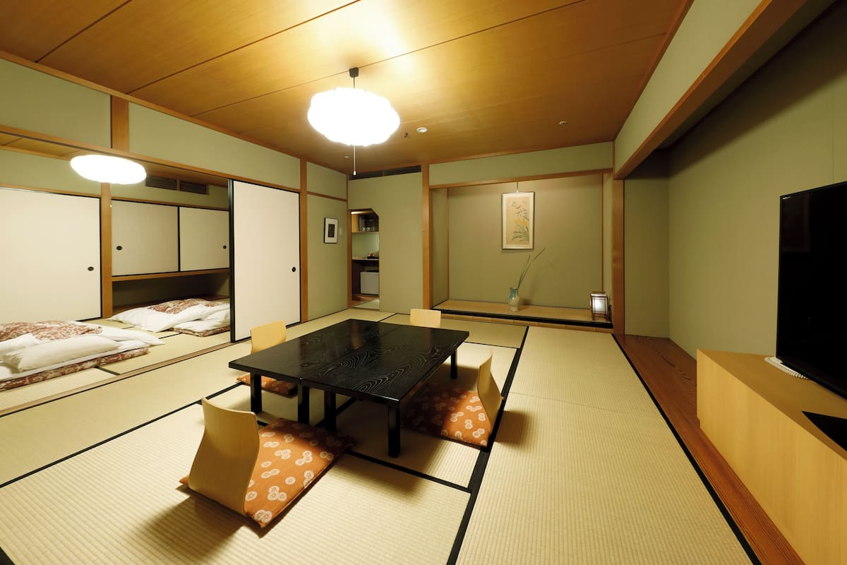 Una habitación tradicional japonesa con suelo de tatami, una mesa baja y un televisor.