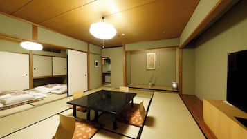 A traditional Japanese-style room with tatami flooring, a low table, and a television.
