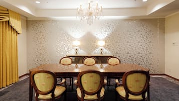 Una sala conferenze con un tavolo rettangolare grande, sei sedie, due lampade a parete e un lampadario.
