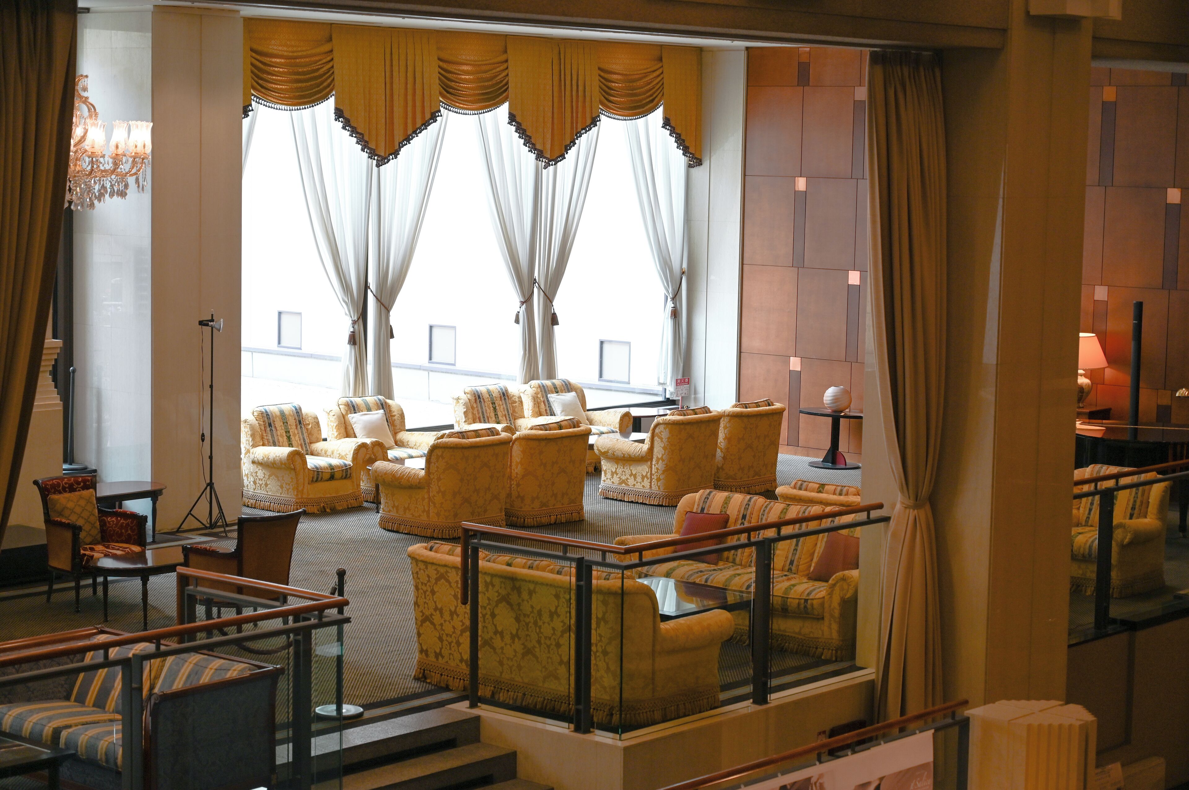 A lobby with a seating area, a chandelier, and a view through large windows.