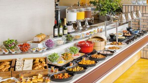 A buffet with various food items, including fruits, vegetables, and meats, arranged on a counter with a brick wall and yellow floor in the background. - Premier Hotel Tsubaki Sapporo (Sapporo)