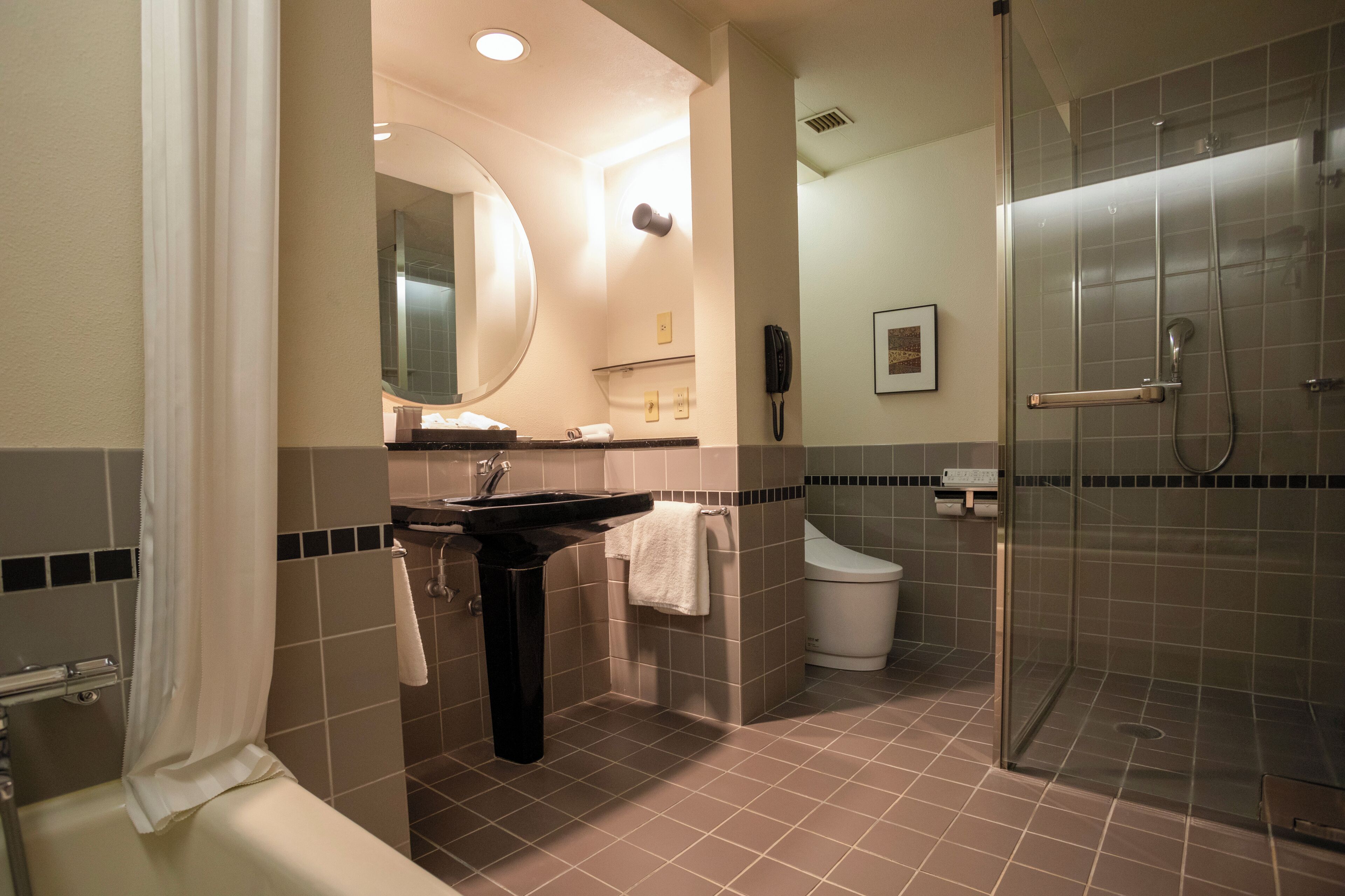 A modern bathroom with a sink, mirror, toilet, and shower.