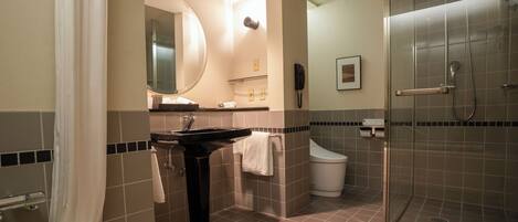 A modern bathroom with a sink, mirror, toilet, and shower.