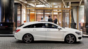 A white luxury car parked in front of a modern hotel entrance with glass doors and a visible interior. - Premier Hotel Tsubaki Sapporo (Sapporo)