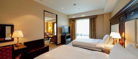 A hotel room with two beds, a desk, a chair, a TV, and a large mirror.