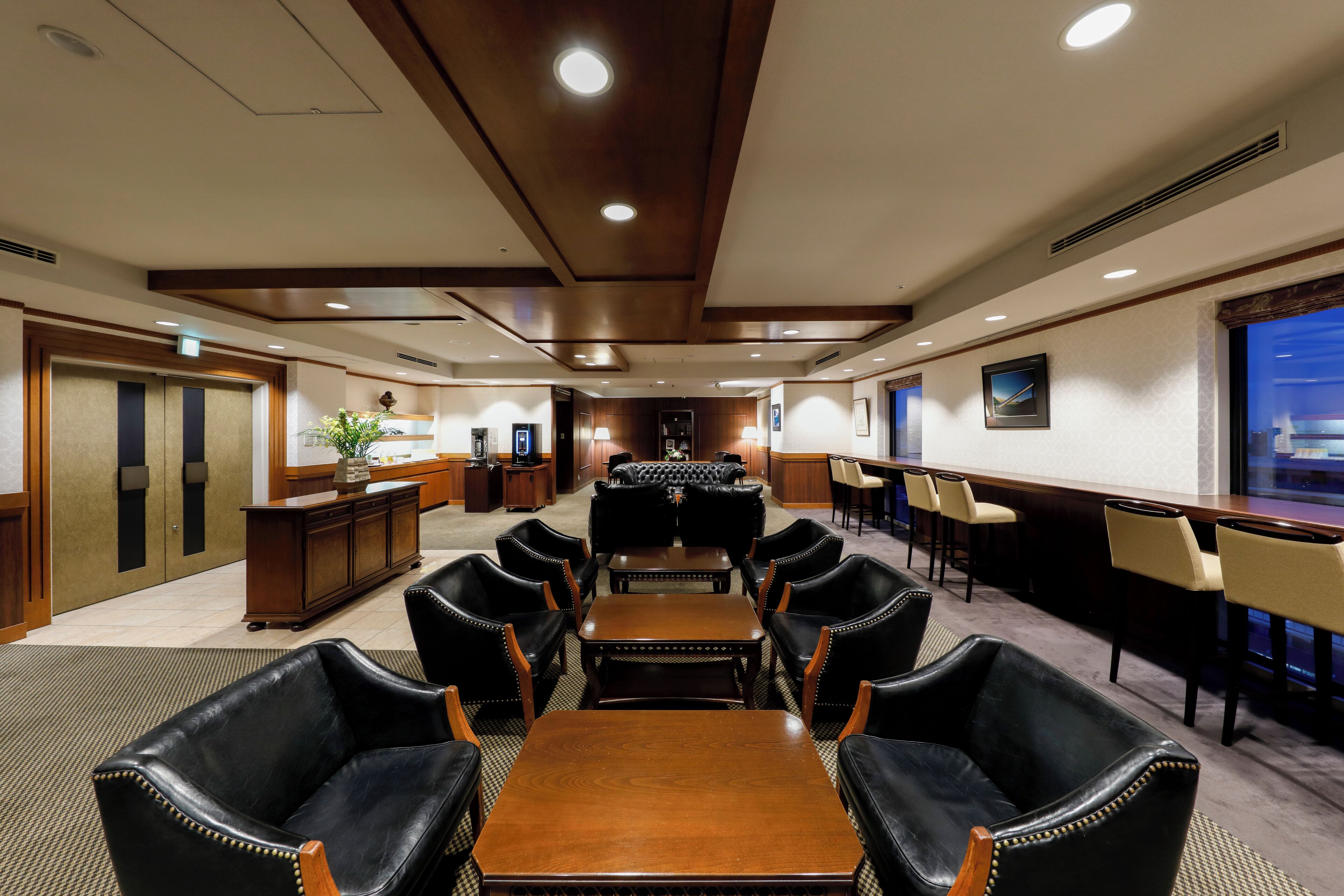 A conference room with a long table and chairs, a reception desk, and a bar area.