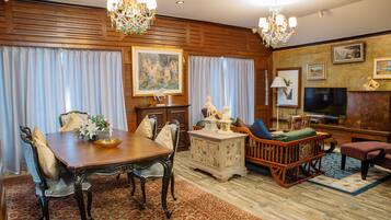 A traditional dining room with a wooden table, chairs, and a chandelier. There is a television and a fireplace in the living area.
