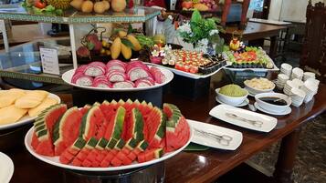 A buffet with various food items including watermelon slices, dragon fruit, and sushi.