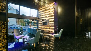 A modern interior with a large bookshelf, comfortable seating, and a view of the street. - Pytloun Grand Hotel Imperial (Liberec)
