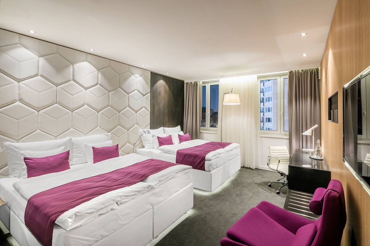 Une chambre d’hôtel avec deux lits, un bureau, une chaise et un téléviseur.