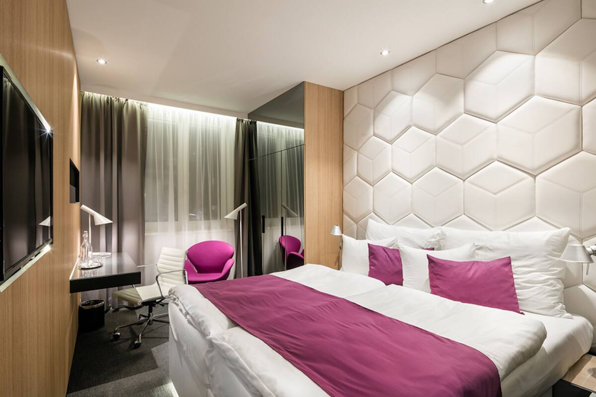 Une chambre d’hôtel moderne équipée d’un grand lit, d’un bureau, d’une chaise et d’un téléviseur.