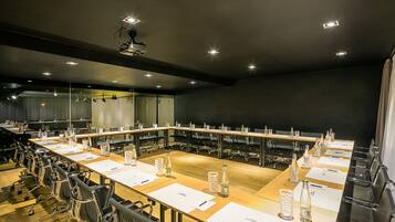 A conference room with a long table, chairs, and a projector.